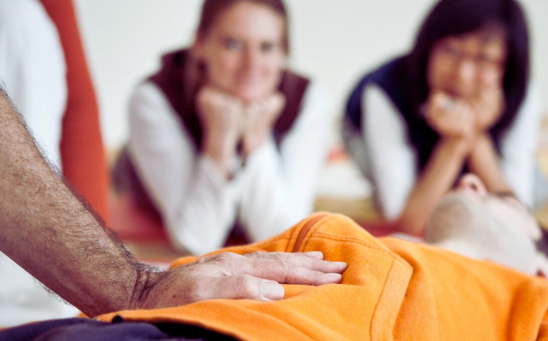 Zwei Frauen während einer Shiatsu-Behandlung – eine behandelt achtsam den Nacken der anderen, die entspannt liegt.